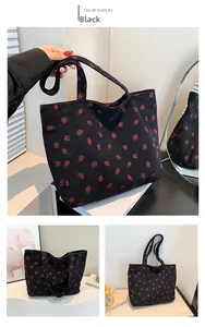 Détail du cabas en velours côtelé noir avec motif fraise rouge et texture du tissu