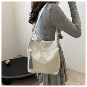 Detail of elegant jacquard tote bag with floral patterns and grey tassel on female shoulder
