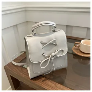 Detail eines grauen Mini-Rucksacks mit Schleifen-Design auf einem Holztisch