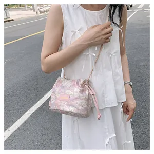 Détail du sac seau rose avec texture artistique, étiquette mode et bandoulière