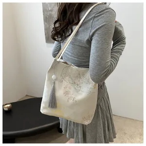 Detail of jacquard floral pattern on beige canvas bag with elegant tassel hanging
