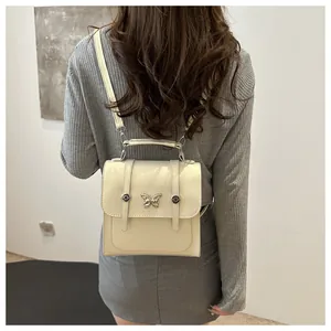 Close-up of gloss beige backpack with a metallic butterfly clasp and top handle