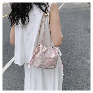 Sac seau rose avec texture jacquard, chaîne dorée et détail de perle dorée ajustable
