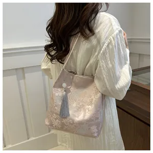 Detail of elegant pink jacquard tote bag with traditional embroidery and tassel decoration