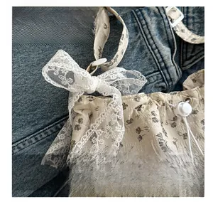 Dettaglio della borsa a secchiello floreale con fiocco in pizzo e coulisse su denim