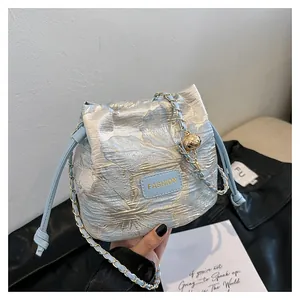 Détail du sac seau en jacquard bleu clair avec motifs floraux dorés et chaîne élégante