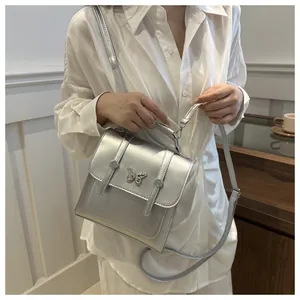 Silver shoulder bag with butterfly metal buckle shown on a model in a lifestyle setting