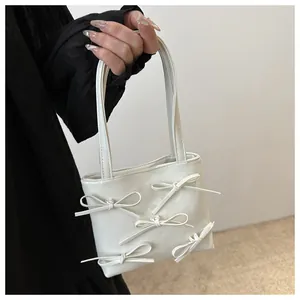 Close-up of white mini tote bag featuring five sweet bows and sleek glossy leather finish