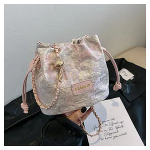 Détail du sac seau en jacquard rose avec chaîne dorée et écusson tendance