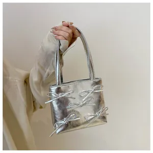 Detail of silver mini tote bag with five 3D metallic bows and chain strap