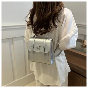 Close-up of metallic silver mini backpack with butterfly detail on a female model