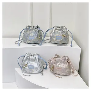 Détail de quatre sacs seaux colorés à cordon et bandoulière chaîne sur supports blancs