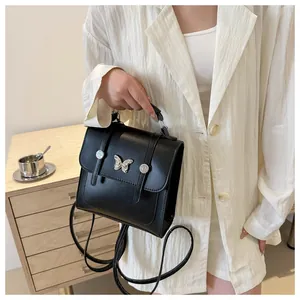Close-up of black retro square bag with silver butterfly accent and textured leather detail