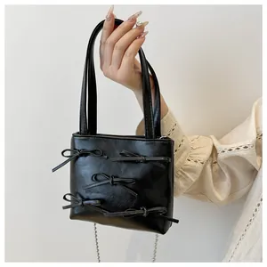 Detail of black mini tote bag with ribbon bows and silver bead chain strap