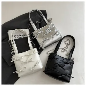 Mini tote bags with ribbon bows in silver, cream, and black showing metal chain straps