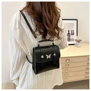 Detail of black faux leather backpack with silver butterfly accent on back of model