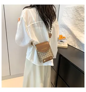 Dettaglio della borsa a tracolla vintage con patta marrone e trama monogramma su modella