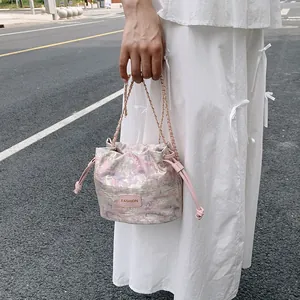 Sac seau en jacquard rose et doré avec bandoulière chaîne et cordon de serrage