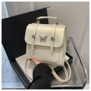 Detail of a pearl white mini backpack with silver butterfly buckle and top handle