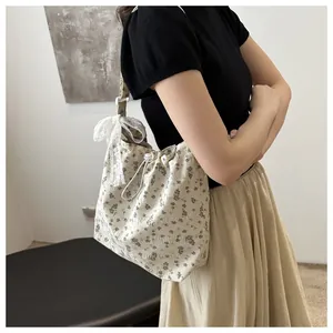 Dettaglio della borsa a fiori con chiusura a coulisse e accessorio fiocco di pizzo bianco