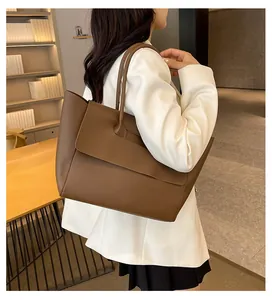 Brown matte leather tote bag detail with large flap closure in a cozy indoor setting
