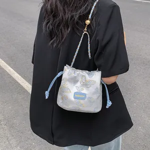 Sac seau en satin bleu clair avec broderie papillon dorée et bandoulière chaîne