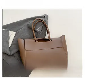 Detailed view of a brown leather tote bag on a grey suit jacket for office styling