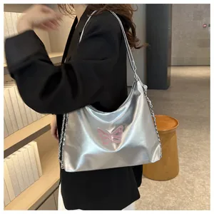 Detail van zilveren metallic schoudertas met roze geborduurde vlinder en ketting