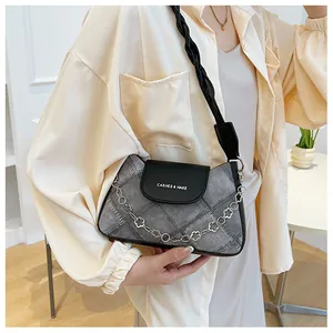 Detail of quilted denim shoulder bag with floral chain and twisted strap worn by a model