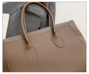 Close-up of the reinforced stitching and leather texture on a brown tote bag handle