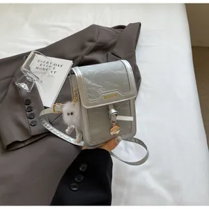 Details der silbernen Mini-Umhängetasche mit Fashion-Logo und Plüsch-Anhänger