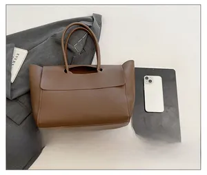 Detail view of the large dark brown tote bag capacity shown with a tablet and phone