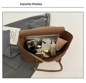 Spacious interior of dark brown leather tote bag holding a laptop and essentials
