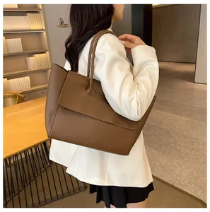 Detailed side view of a large brown leather tote bag worn as a shoulder bag
