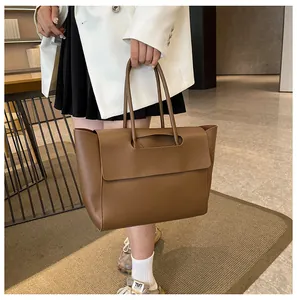 Brown matte leather tote bag shown on model with shoulder strap and minimalist design