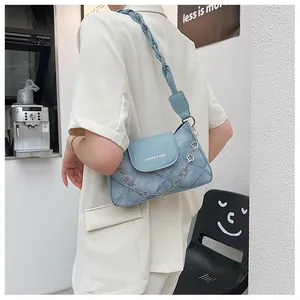 Detail of light blue denim texture shoulder bag with woven strap and clover metal chain