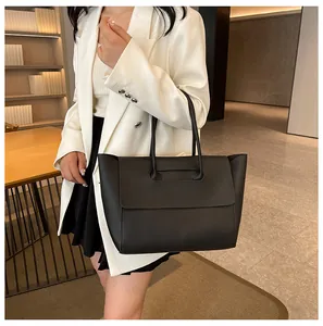 Close-up of a large black leather tote bag with a minimalist flap and long handles