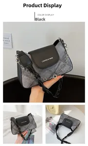 Detail of grey denim shoulder bag with black flap, chain strap and floral charm