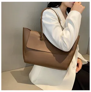 Detailed side view of the large dark brown tote bag on a model wearing a white blazer