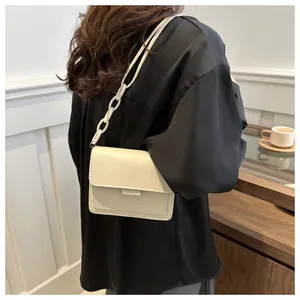 Dettaglio di una borsa a tracolla bianco crema con catena decorativa in plastica per donne