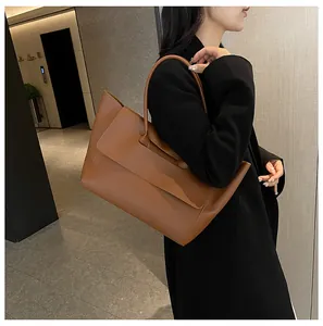 Close-up of brown matte faux leather tote bag with thick circular handle and top flap cover