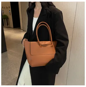 Detail of minimalist brown tote bag with smooth matte leather and fold-over top closure