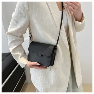 Dettaglio della borsa a tracolla minimalista in pelle nera con patta e manico decorativo