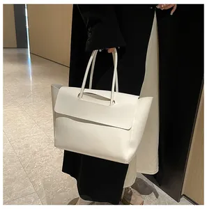 Detailed view of a white minimalist large tote bag with slim handles in a street style setting