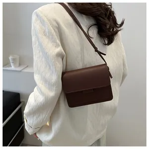 Vista laterale di una borsa a tracolla marrone scuro vintage con blazer beige