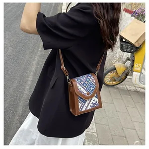 Close-up of a vintage square crossbody bag with woven texture and brown leather trim