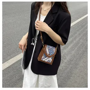 Outdoor street view of a vintage woven crossbody bag worn by a model in black and white