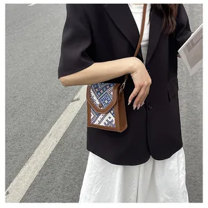 Detail view of a vintage brown crossbody bag with colorful ethnic woven pattern on the flap