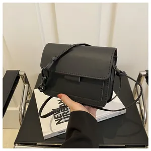 Dettaglio della borsa a tracolla in pelle nera con decorazione a nodo e cuciture su sedia