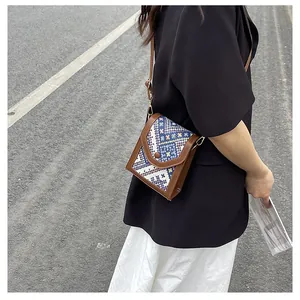 Outdoor shot of a woven crossbody bag with geometric patterns and brown leather accents